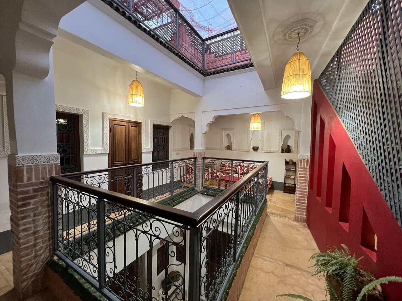 Ein mehrgeschossiges Interieur mit einer zentralen Treppe, dekorativen Geländern und einem Oberlicht.