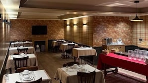 Un restaurante con varias mesas, un muro de ladrillo y un mantel rojo.