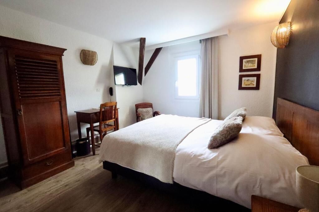 Un dormitorio con cama, escritorio, silla, armario y televisor.