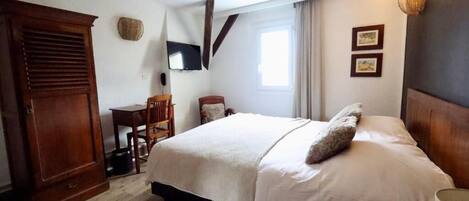 Un dormitorio con cama, escritorio, silla, armario y televisor.