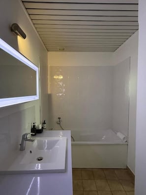A bathroom with a white sink, mirror, and shower.