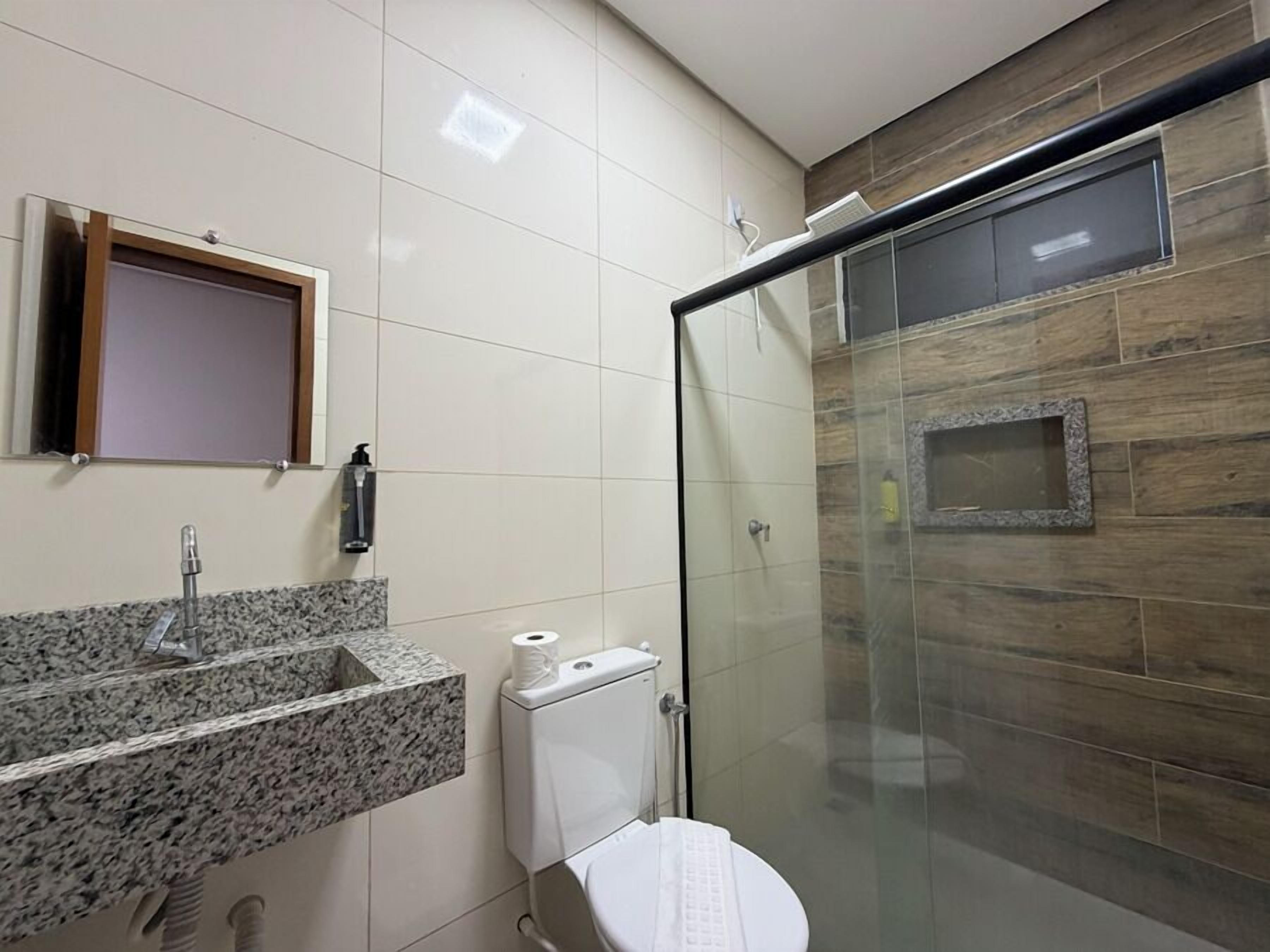 A bathroom with a granite countertop sink, a toilet, and a glass shower enclosure.