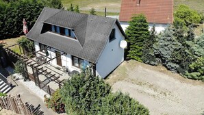 Uma casa com telhado inclinado, antena parabólica visível e calçada de asfalto.