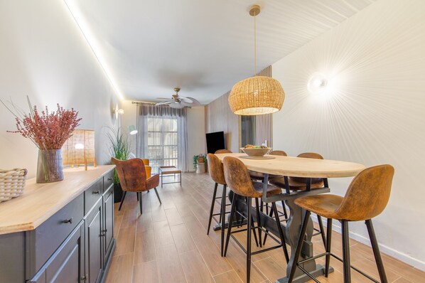 Eine moderne Küche mit Essbereich, ausgestattet mit einem großen Holztisch, Barhocker und einer hängenden Leuchte.