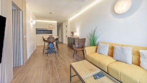 Una sala de estar moderna con un sofá amarillo, una mesa de centro y un comedor con mesa y sillas.