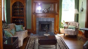 A living room with a fireplace, a sofa, a chair, a coffee table, and a bookshelf. - A La Gallarie Bed and Breakfast  (Niagara-on-the-Lake)