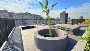 Kattoterassi, jossa on pyöreä istutusastia, poreallas ja oleskelualue.
