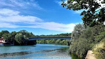 A river with a bridge, trees, and a concrete path alongside.