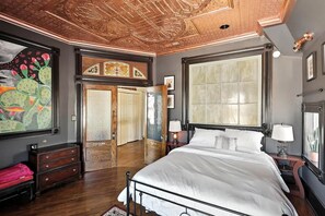 A bedroom with a large bed, a wooden dresser, a mirror, and a door with 'STEP DOWN' and 'STEP UP' signs. - Ravenwolf House - Odd & Elegant Downtown ABQ Gem (Albuquerque)