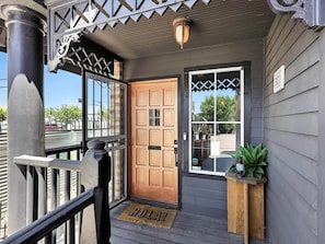 A wooden door with a glass panel, a porch with a bench, and a doormat. - Ravenwolf House - Odd & Elegant Downtown ABQ Gem (Albuquerque)