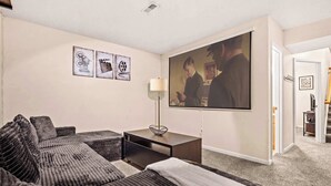 A modern living room with a large flat-screen TV, a sofa, a coffee table, and a lamp. - Cozy Family Retreat Near Fort Campbell, Sleeps 8 (Clarksville)