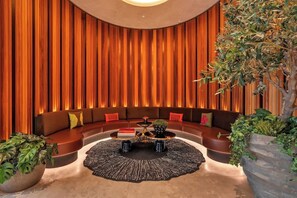 Ein modernes Interieur mit einer gebogenen Couch, einem runden Couchtisch und einer großen Pflanze.