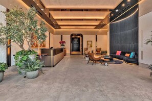 Eine moderne Lobby mit Empfangstresen, Sitzgelegenheiten und Topfpflanzen.
