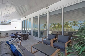Eine Terrasse im Freien mit einer Couch, Stühlen, einem Tisch und Blick aufs Meer.