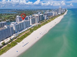 Eine Küstenstadt mit hohen Wolkenkratzern, einem weiten Sandstrand und einem klaren, blauen Meer.