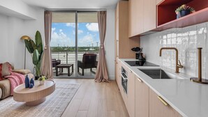A modern kitchen with a large window, sliding doors to a balcony, and a dining area. - Monthly Stay Studio · Midtown Miami, Free Parking (Miami)
