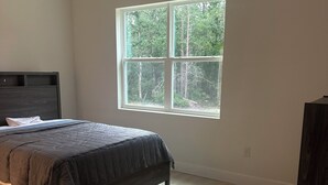 A bedroom with a bed, a window, and a dark piece of furniture.