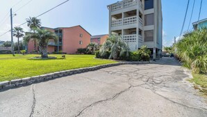 A multi-story building with balconies, a parking area, and a well-maintained lawn. - Beachfront Paradise with Stunning Gulf Views (Gulf Shores)