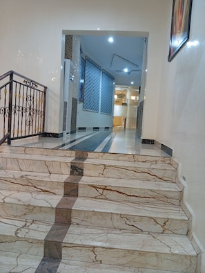 A marble staircase leading to a room with a patterned curtain and a chandelier.