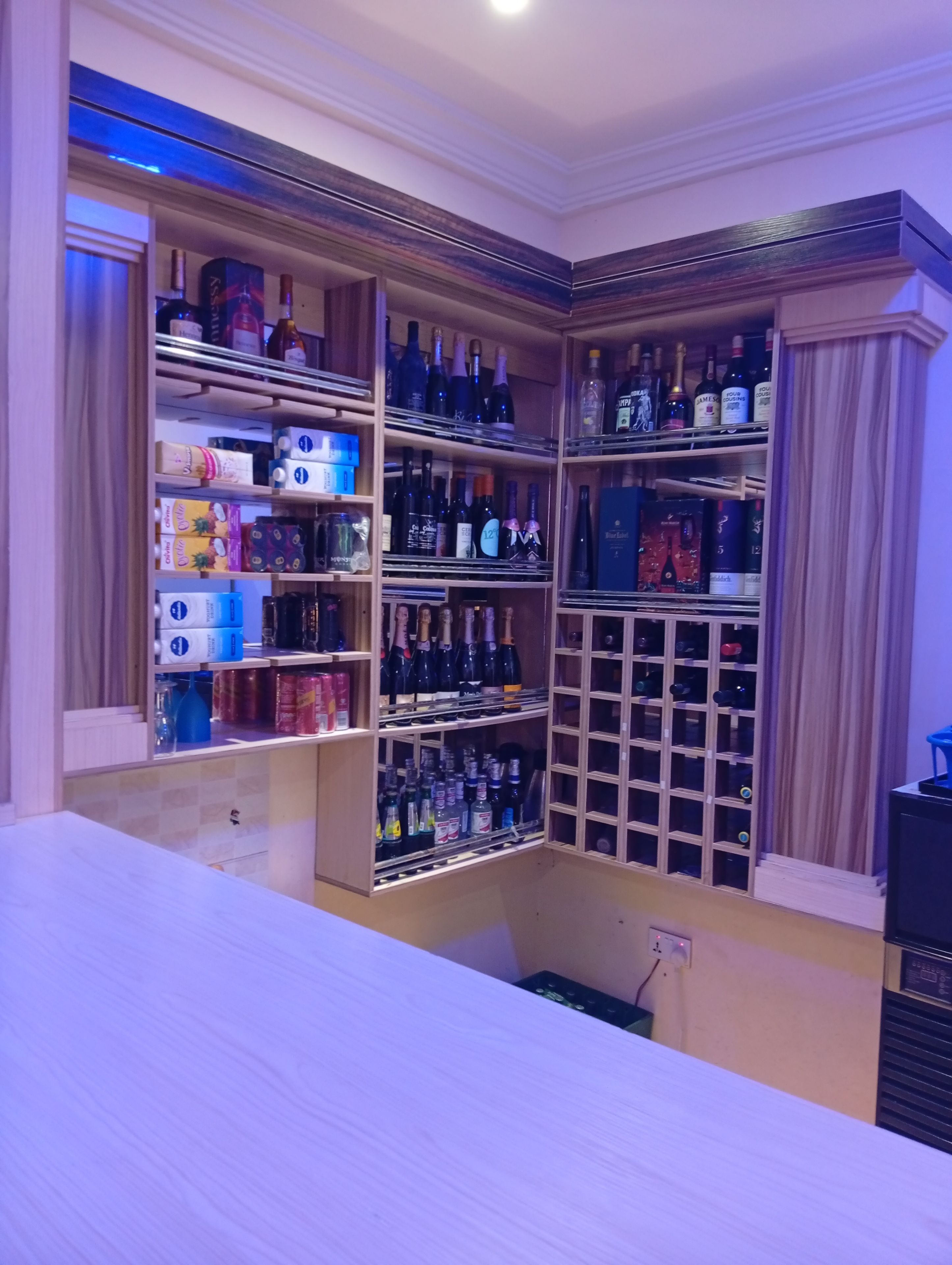 Un bar bien organisé, doté de plusieurs étagères et contenant une variété de bouteilles.