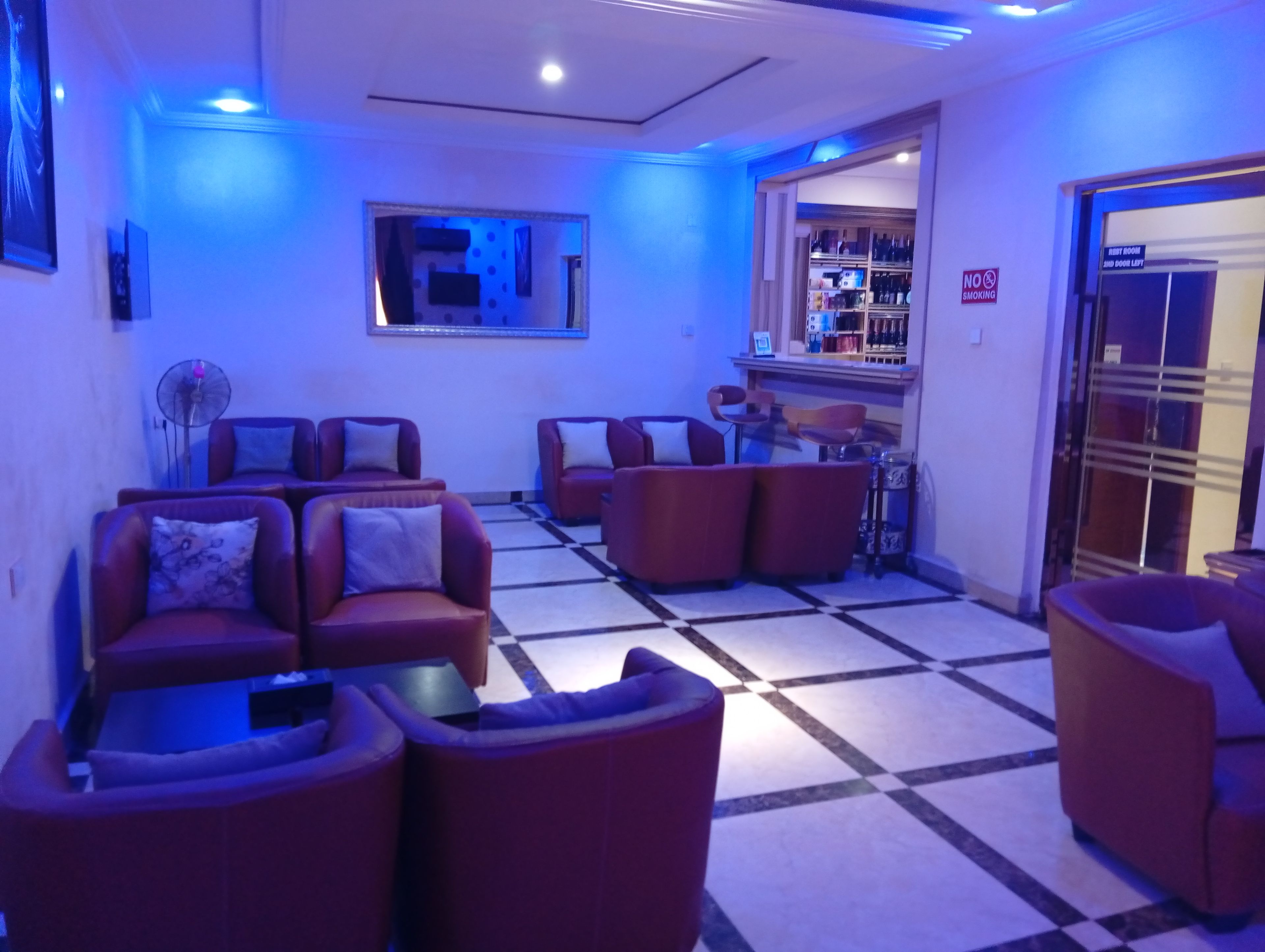 A lobby with red sofas, a bar area, and a 'No Smoking' sign.