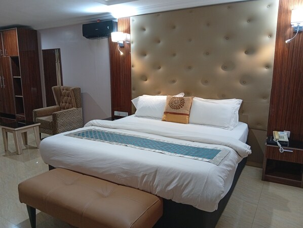 A hotel room with a large bed, a chair, a bedside table, and a wall-mounted telephone.