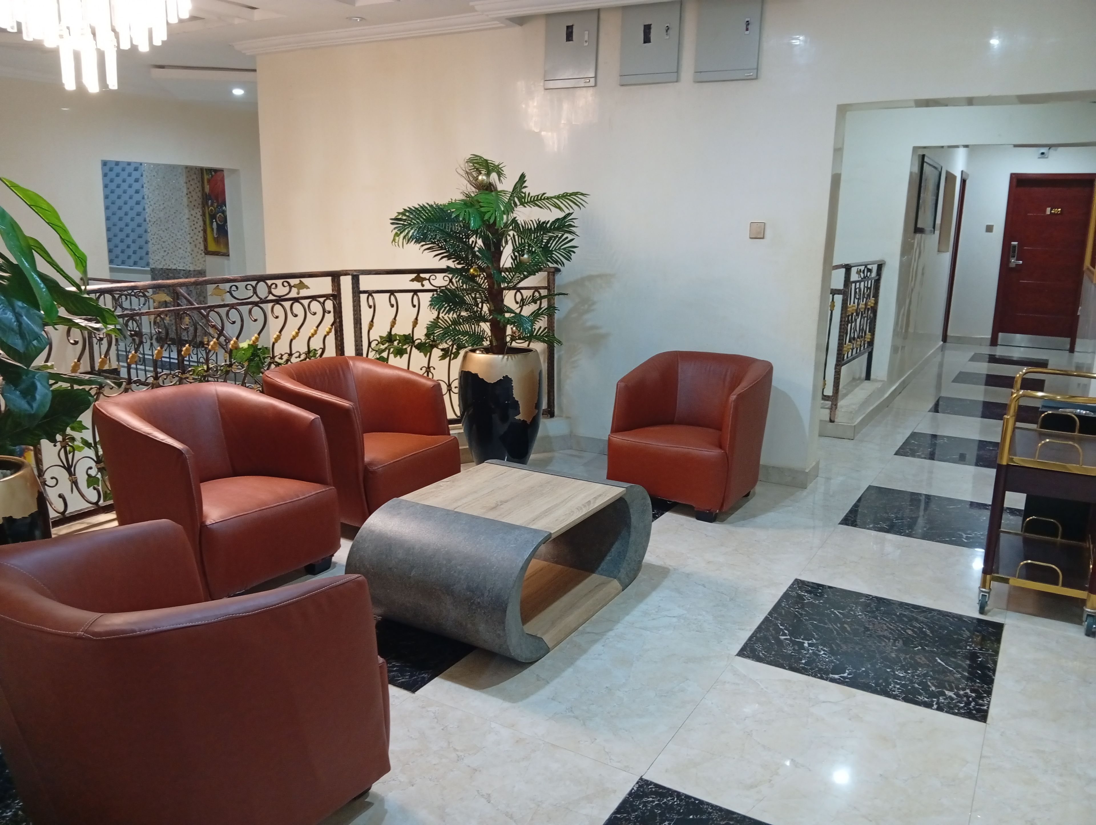Un hall con sillones de cuero rojo, una mesa de centro, una planta en maceta y una escalera.
