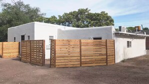 A white building with a flat roof, a wooden fence, and a clear sky. - Downtown District - Modern Apt Yard, King Bed, W/D (Albuquerque)