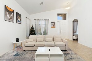 A living room with a beige sofa, a white coffee table, and a Christmas tree. - Spacious 4BR Phoenix Home with Private Pool! (Phoenix)