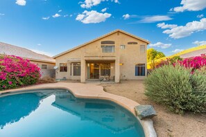 A house with a swimming pool, a balcony, and a garden with pink flowers. - Spacious 4BR Phoenix Home with Private Pool! (Phoenix)