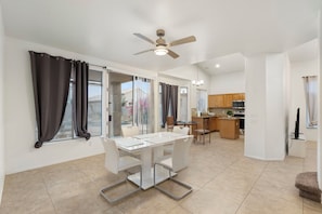 A spacious living area with a dining table, a ceiling fan, and a kitchen in the background. - Spacious 4BR Phoenix Home with Private Pool! (Phoenix)