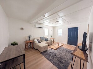 A modern living room with a sofa, coffee table, and a TV stand. - Downtown District - Modern Apt Yard, King Bed, W/D (Albuquerque)