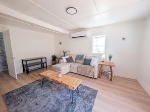 A modern living room with a sofa, a coffee table, a side table, and a potted plant. - Downtown District - Modern Apt Yard, King Bed, W/D (Albuquerque)