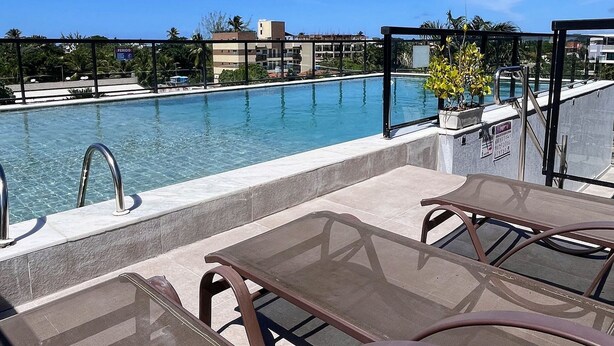 Une piscine sur le toit, avec une eau d’un bleu limpide, des chaises longues et une vue sur les bâtiments en arrière-plan.