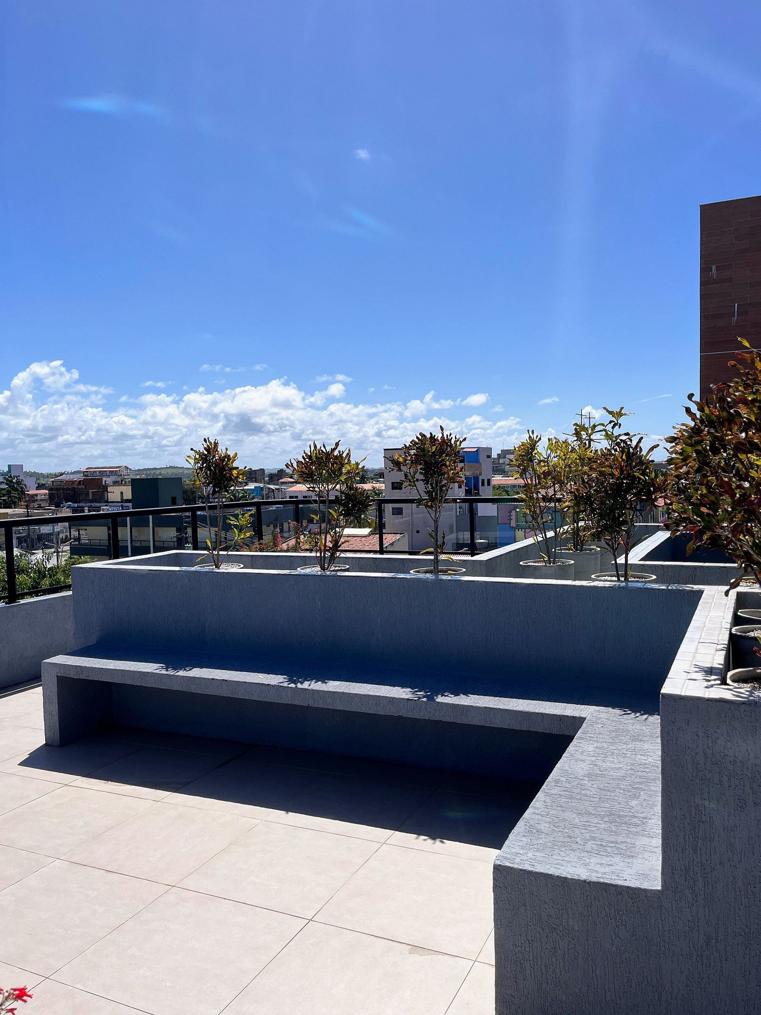 Una terraza en la azotea con zona de estar, plantas en macetas y vistas de la ciudad.
