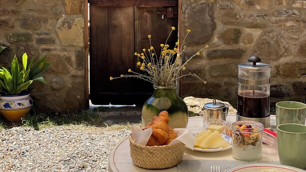 A stone wall, a wooden door, a table with food, and a potted plant.