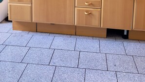 Een keuken met houten kastjes, een magnetron, een spoelbak en een aanrecht.