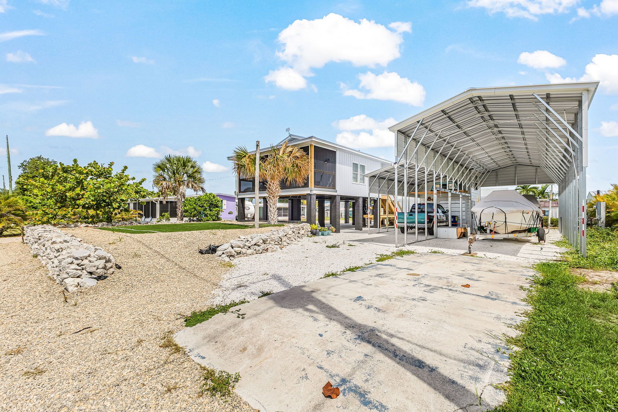 A modern building with a covered outdoor area, a paved driveway, and a landscaped garden.