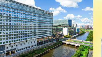 Un hotel moderno con vista al río, un puente y un paisaje urbano al fondo.