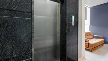 Un ascensor moderno con acabados metálicos, junto a una pared con superficie texturizada.