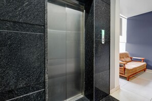 A modern elevator with a metallic finish, adjacent to a wall with a textured surface. - Deluxe Brookefield Mall Bangalore (Bengaluru)