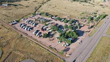 Vista aèria d'un campament amb autocaravanes i tendes, envoltat de camps oberts i una carretera.