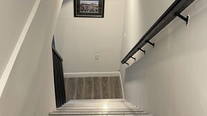 En modern trappa med träpanel, ett metallräcke och en inramad tavla på väggen.