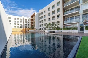 A modern hotel with a swimming pool, multiple balconies, and outdoor seating areas. - Best Location in Cabo 3BR Condo Walk to Everything (Cabo San Lucas)