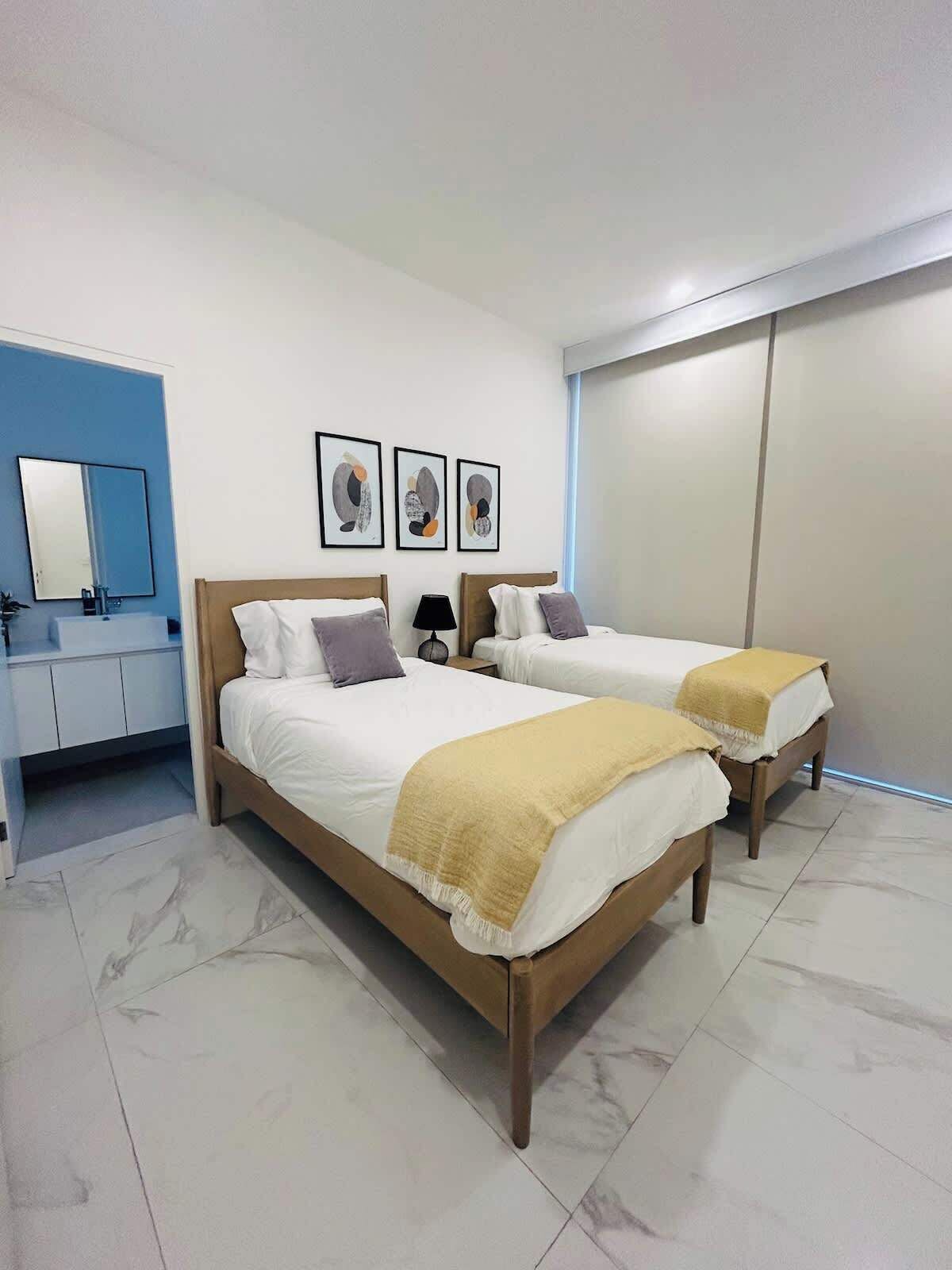 Een hotelkamer met twee bedden, een badkamer en een groot raam.