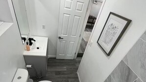 Une salle de bain équipée d’une baignoire, de toilettes, d’un lavabo et d’une porte donnant sur une autre pièce.