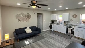 Une cuisine moderne équipée d’un four encastré, d’une table à manger et d’un ventilateur de plafond.