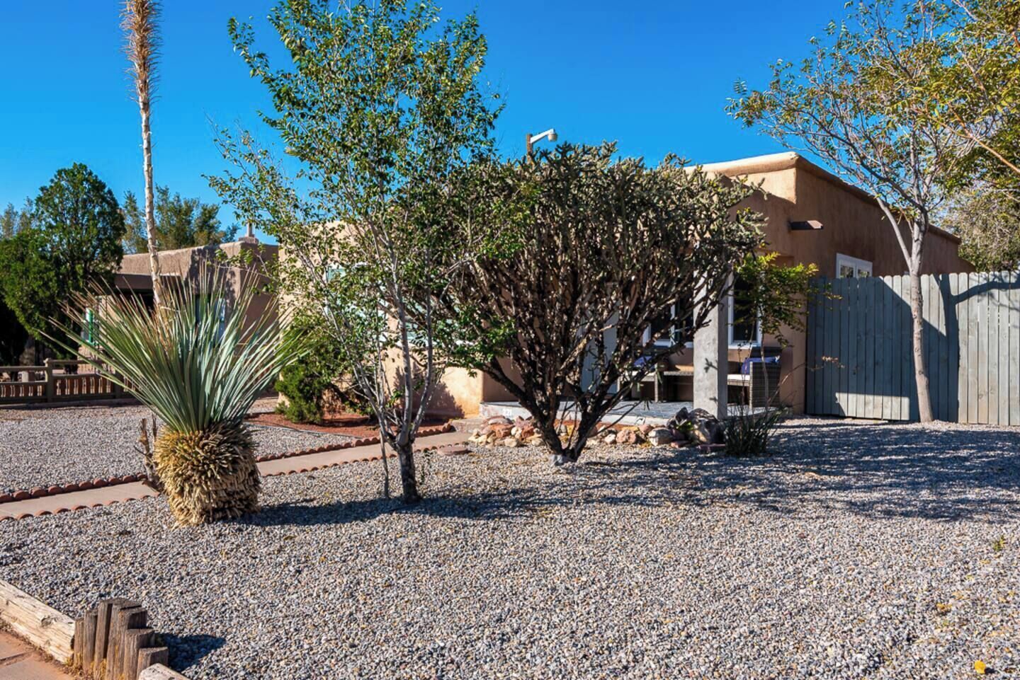 Zona residencial con una casa, camino de grava y varios árboles.