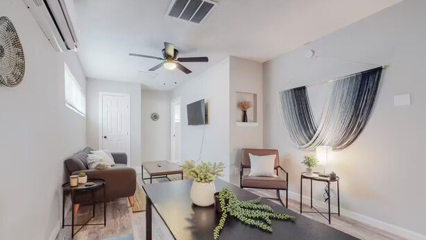 En moderne stue med sofa, sofabord og spisebord med en plante som midtpunkt.