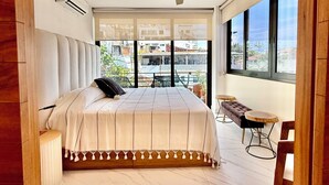 Een moderne slaapkamer met een groot bed, een plafondventilator en uitzicht op de stad door grote ramen.